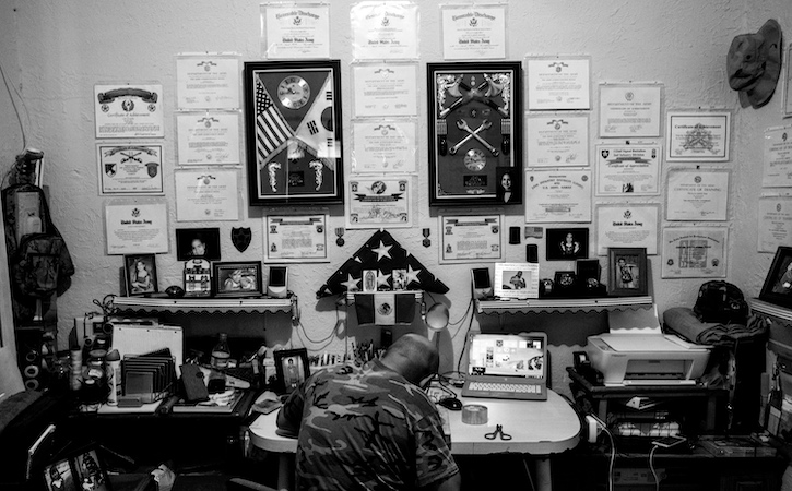 Man at desk with back to us and wall full of awards